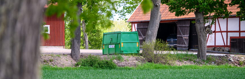 Hyrd grön container står på gårdsplan på landsbygden