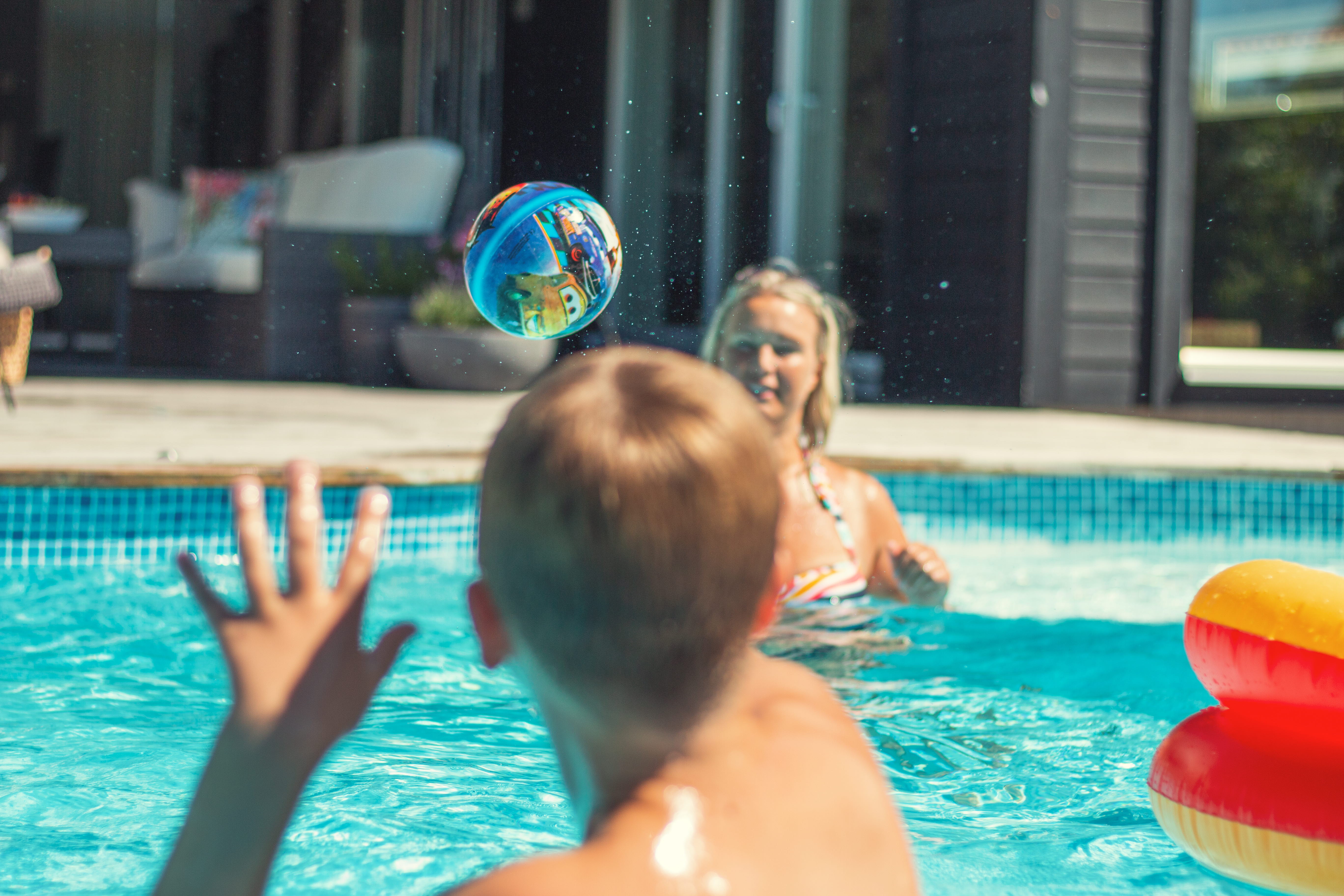 En kvinna och ett barn leker i en pool