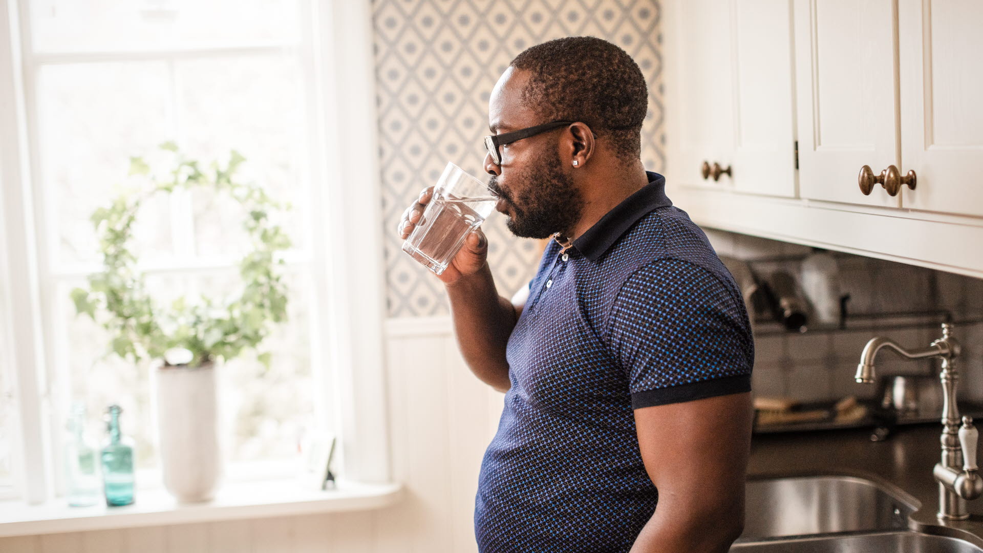 Man dricker vatten i köket