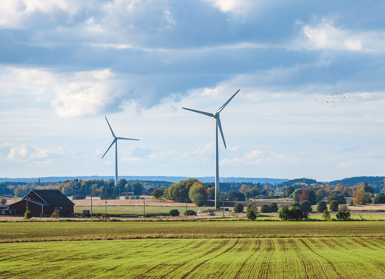 Vindkraftverk mot en blå himmel på slätten i Mjölby