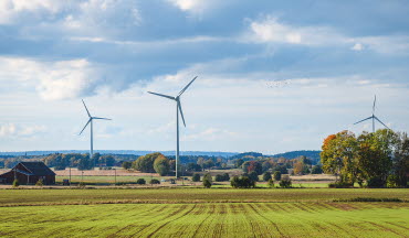 Vindkraftverk mot en blå himmel på slätten i Mjölby