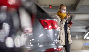 Kvinna i pakeringshus kollar på mobil (foto)