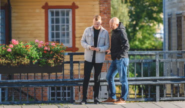 Kunder står på stan i Mjölby och tittar på mobilen