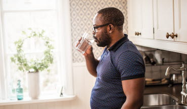 Man dricker vatten i köket