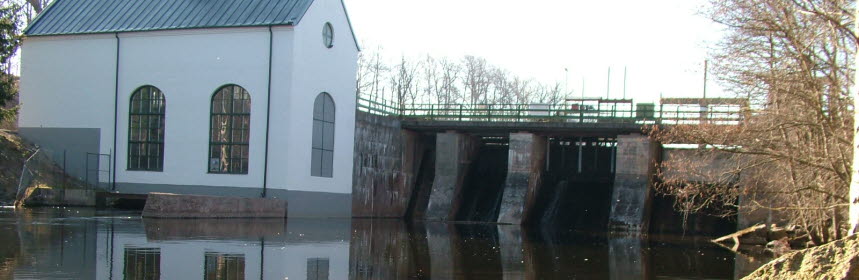 Vattenkraft med pumphus i Flemminge, spegelblankt vatten. Foto. 