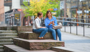 Kunder pratar och tittar på mobil på stan i Linköping