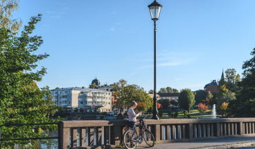 Kund står vid broräcke i Mjölby och tittar på mobilen