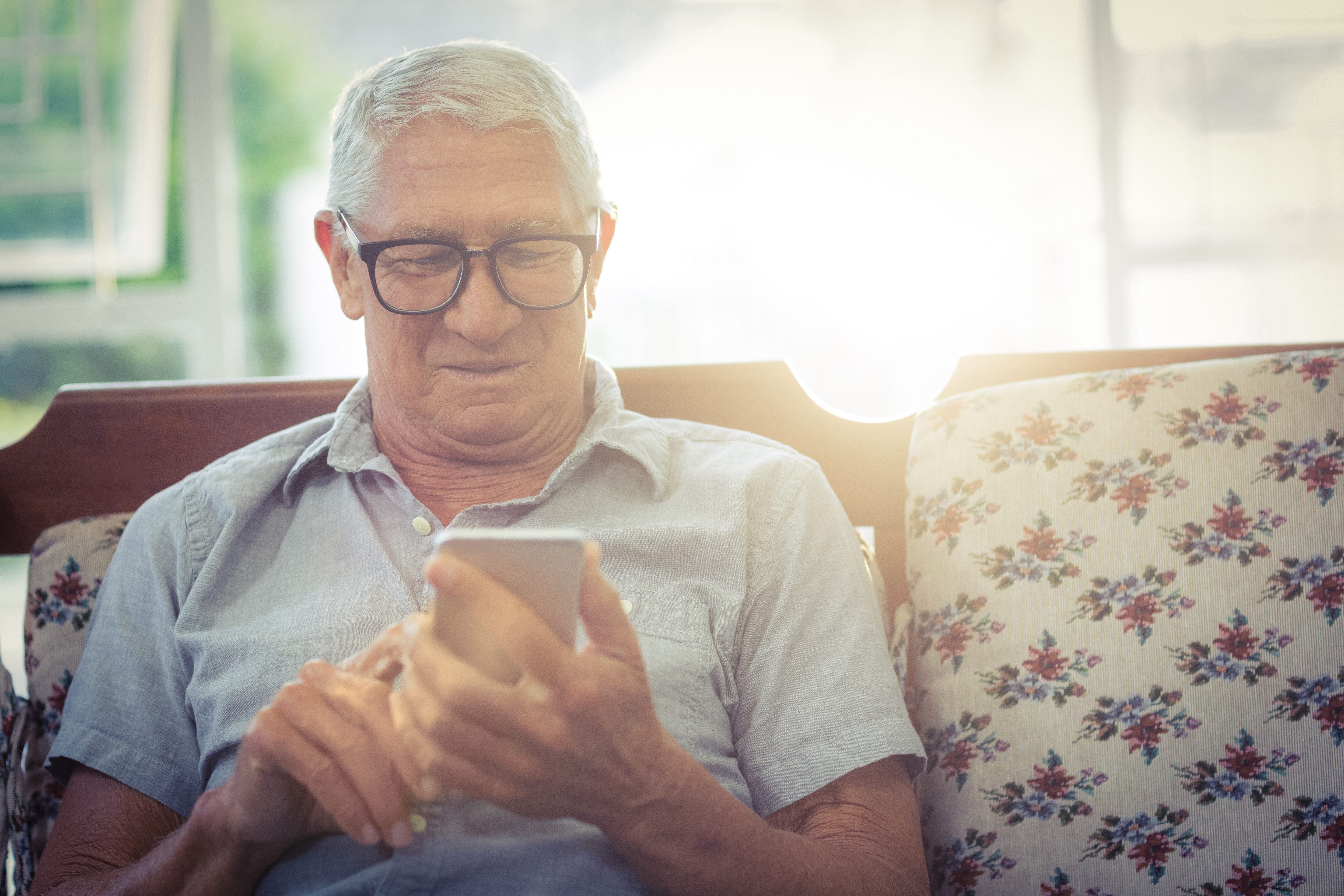 Äldre man tittar på en smartphone (foto)