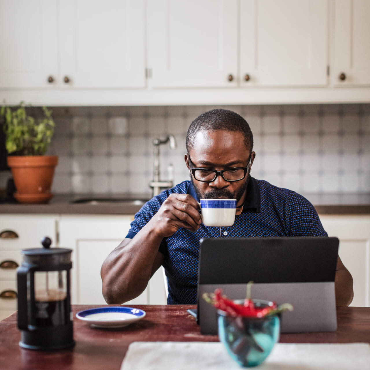 Man dricker kaffe vid datorn i köket